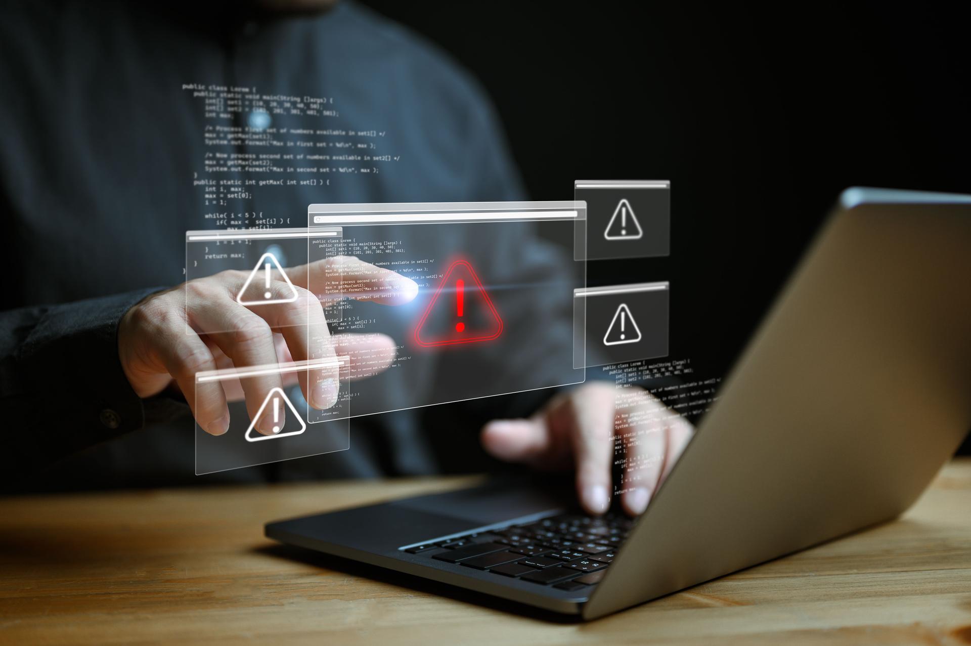 Businessman or it staffs, programmer, developer using computer laptop with triangle caution warning sign for notification error and maintenance concept. Virus detected warning, Cybercrime protection